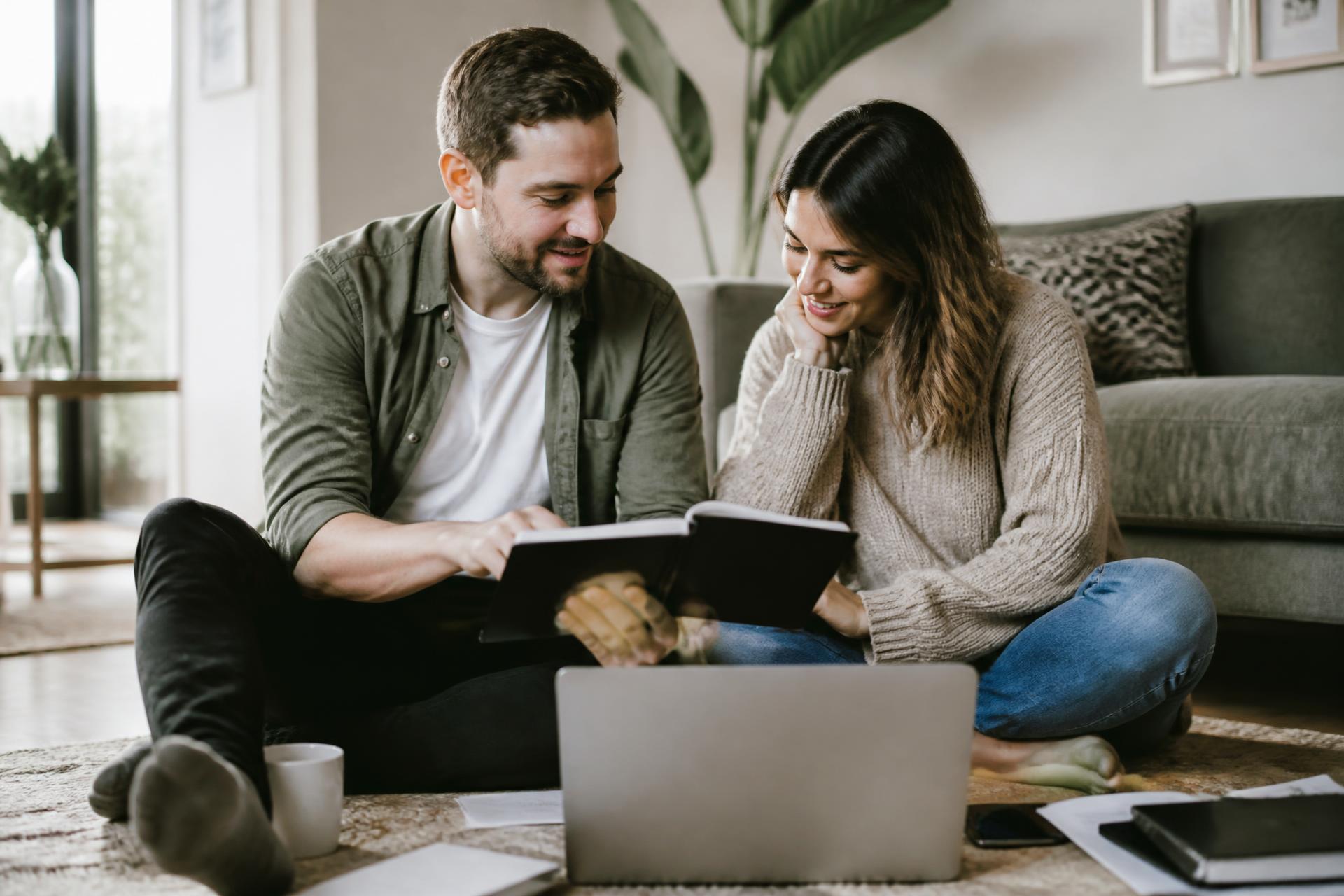 A couple planning together on the floor of their living room